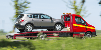 Red tow truck towing a silver SUV.